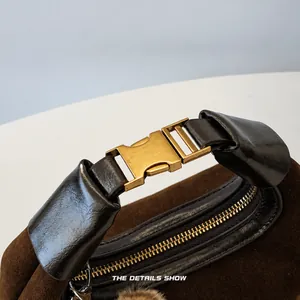 Detail of dark brown suede bag featuring black leather handle and vintage gold metal clasp