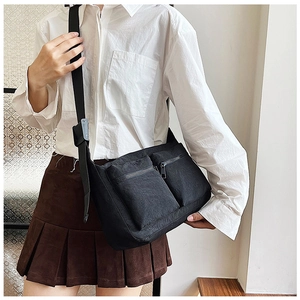 Detail of black nylon crossbody bag with two front zipper pockets and adjustable strap