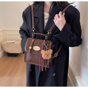Gros plan d'un sac à main marron vintage avec un ours en peluche et accessoire rayé