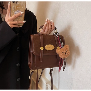 Détail du sac à main vintage en cuir marron avec daim et pendentif ours mignon