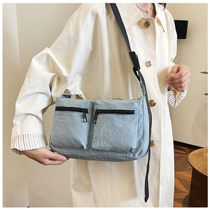 Detail of light blue nylon crossbody bag with dual parallel front zipper pockets