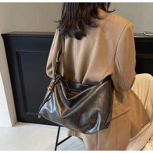 Close-up of the black matte tote bag featuring a gold logo and braided rope detail
