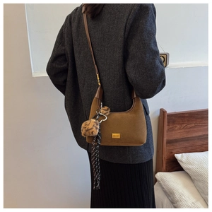 Brown suede crescent bag with leopard fur ball and silk scarf on a winter coat