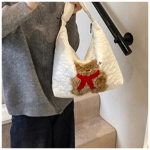Detail einer weißen Stepptasche mit einem süßen Plüschbären und roter Krawatte