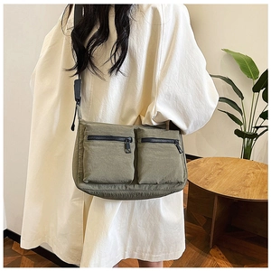 Detailed view of army green nylon crossbody bag with dual zip pockets on model