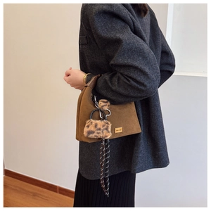 Close-up of brown suede hobo bag with leopard print charm and woven tassel detail