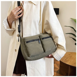 Detail view of military green nylon crossbody bag with multiple front zipper pockets