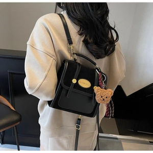 Détails du sac à bandoulière noir contrasté avec boucles dorées et breloque ourson