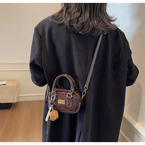 Detailed back view of a model wearing a mini dark brown crossbody pillow bag with charms