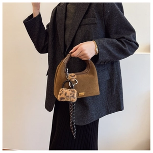 Detail of brown suede dumpling bag with gold logo and leopard print plush charm