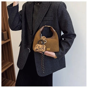 Detail of brown suede dumpling bag featuring leopard charm and polka dot scarf