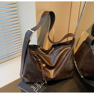 Detail of dark brown leather tote with woven charm and adjustable wide strap
