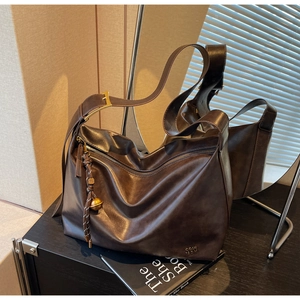Detail of dark brown leather tote with woven zipper pull and golden orb charm accessory