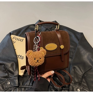 Detail of dark brown leather and suede backpack with gold hardware and plush bear charm
