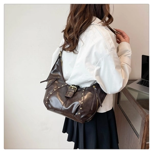 Detail of dark brown vintage shoulder bag with golden studs and buckle on model