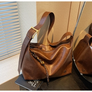 Detail of vintage brown tote bag with metal buckle and woven tassel hanging ornament