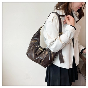 Detailed close-up of dark brown vintage hobo bag with gold studs and belt buckle