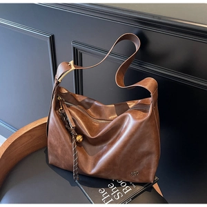 Close-up of vintage brown leather tote bag with gold buckle and brand logo detail