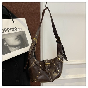 Detail view of coffee brown crescent bag featuring vintage rivets and metal zippers