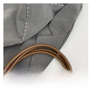 Detail of grey textured fabric tote bag featuring brown leather strap and contrast stitching