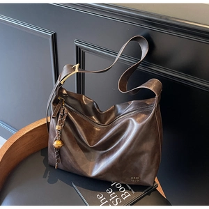 Detail of deep brown oil-wax leather texture and gold hardware on large hobo tote bag