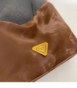 Dettaglio della borsa in pelle marrone lucida con placca logo in metallo dorato