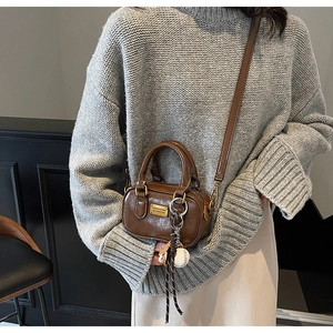 Close-up of brown mini pillow bag with golden plate and creative baseball charm detail
