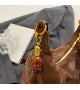 Dettaglio borsa in pelle marrone con anelli dorati e perline ambrate decorative