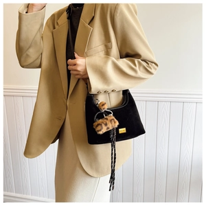 Detail of black suede hobo bag with gold logo and leopard print faux fur charm accessory