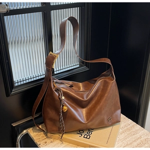 Close-up of vintage brown leather tote showing wide strap and embossed brand logo