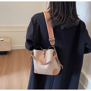 Detail of two-tone bucket bag with lychee texture and wide fabric shoulder strap