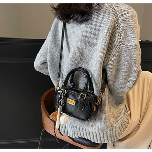Close-up of black retro boston bag with glossy texture and sporty baseball charm