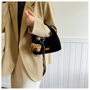 Detail of black suede hobo bag with leopard pom-pom and striped ribbon accent