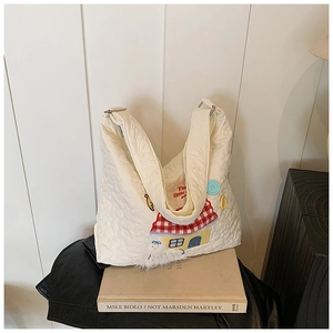 Detailansicht der weißen Stepptasche mit Cartoon-Stickerei und flauschigem Anhänger-Detail