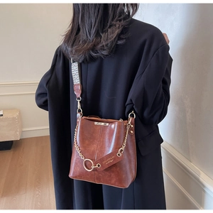 Détail du sac seau vintage marron avec cuir texturé, sangle large et chaîne