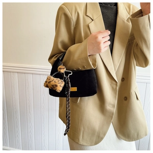 Detail of black suede matte handbag with leopard print charm and woven tassel accent