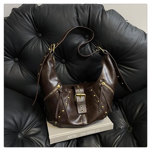 Detail view of dark brown hobo bag featuring golden rivets, zipper tassels, and oil wax texture