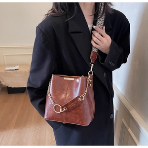Gros plan du sac seau vintage marron avec bandoulière tissée et détails de chaîne