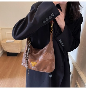 Dettaglio della borsa hobo marrone con logo dorato e accessorio foulard a righe sottili
