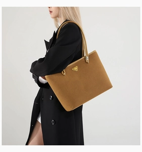 Detailed view of brown suede tote bag with golden triangle logo on clean white background