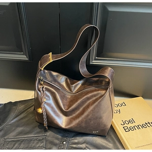 Detail of dark brown leather tote bag with gold logo, metal buckle and bell charm