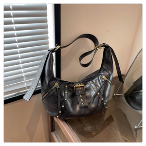 Detail of dark brown vintage dumpling bag with matte leather and golden rivets