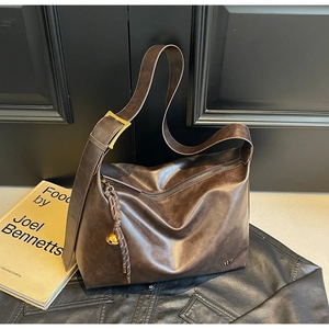 Detail of vintage brown leather tote bag showing wide strap with antique brass buckle
