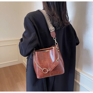 Sac seau marron avec surpiqûres, chaîne dorée et large bandoulière à motif ethnique