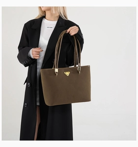 Detail of dark brown tote bag with golden triangle logo on professional black blazer