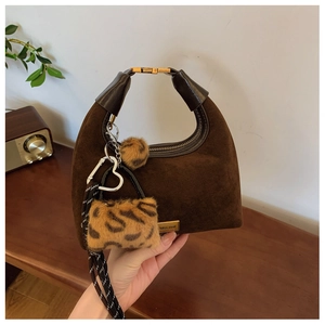 Detail of brown suede dumpling bag with leopard faux fur charm and metallic accents