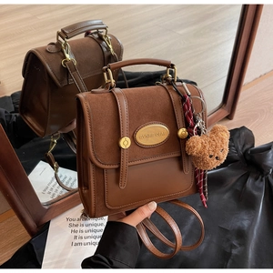 Detail of vintage brown backpack with plush bear charm and plaid scarf accessory
