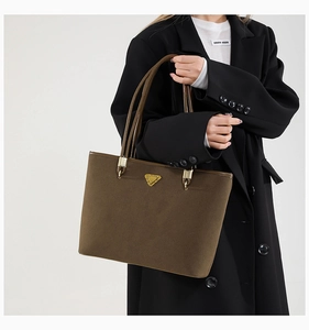 Detailed close-up of dark brown suede tote bag featuring round handles and golden hardware