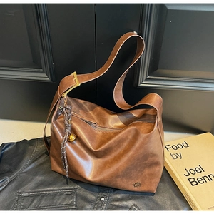 Detailed close-up of brown leather tote featuring gold buckle and knot pendant