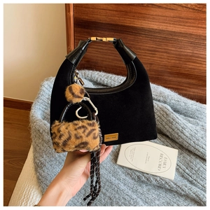 Detail of matte black suede dumpling bag with metal logo and leopard print charm accessory